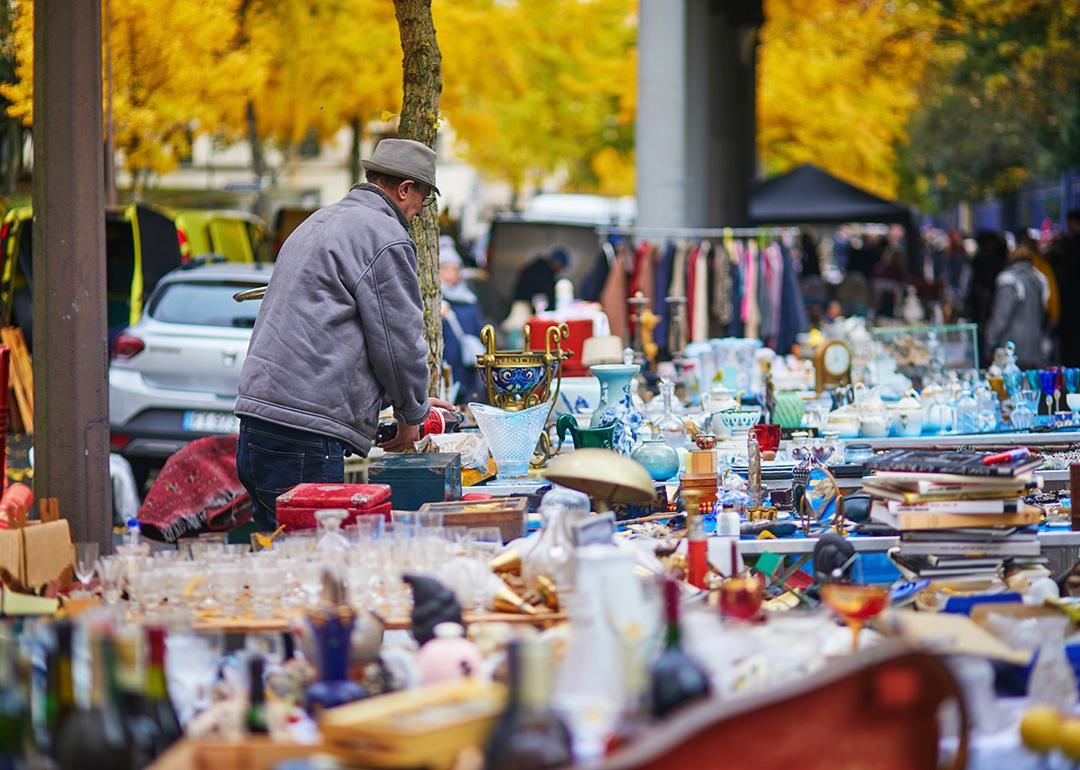 A seller preparing antique items for sale at a flea market in Paris, France.