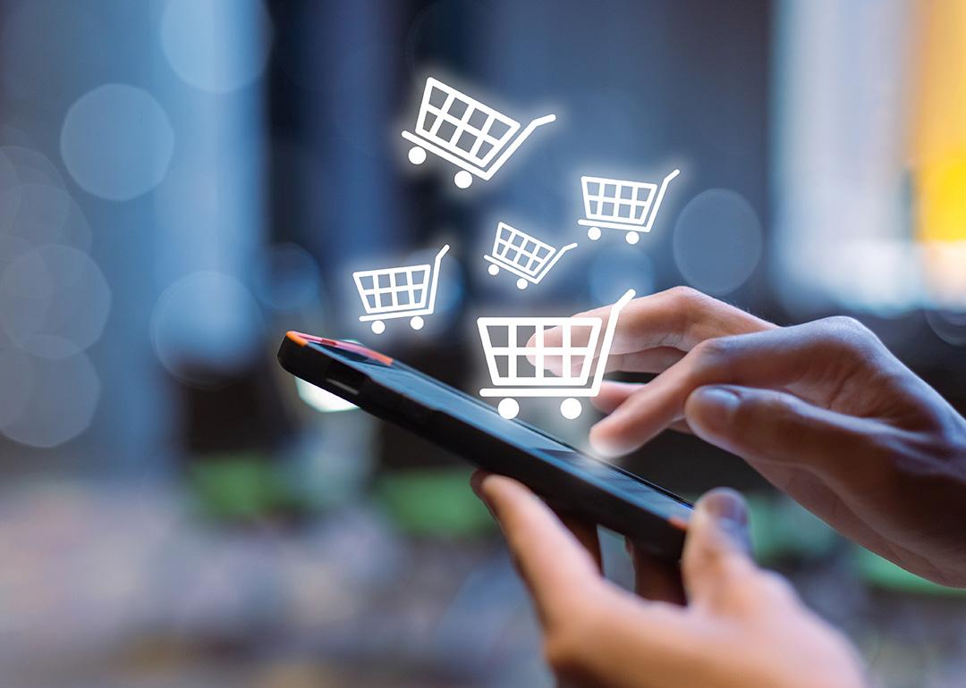 Shopping cart icons over a person using a shopping app on a smartphone.