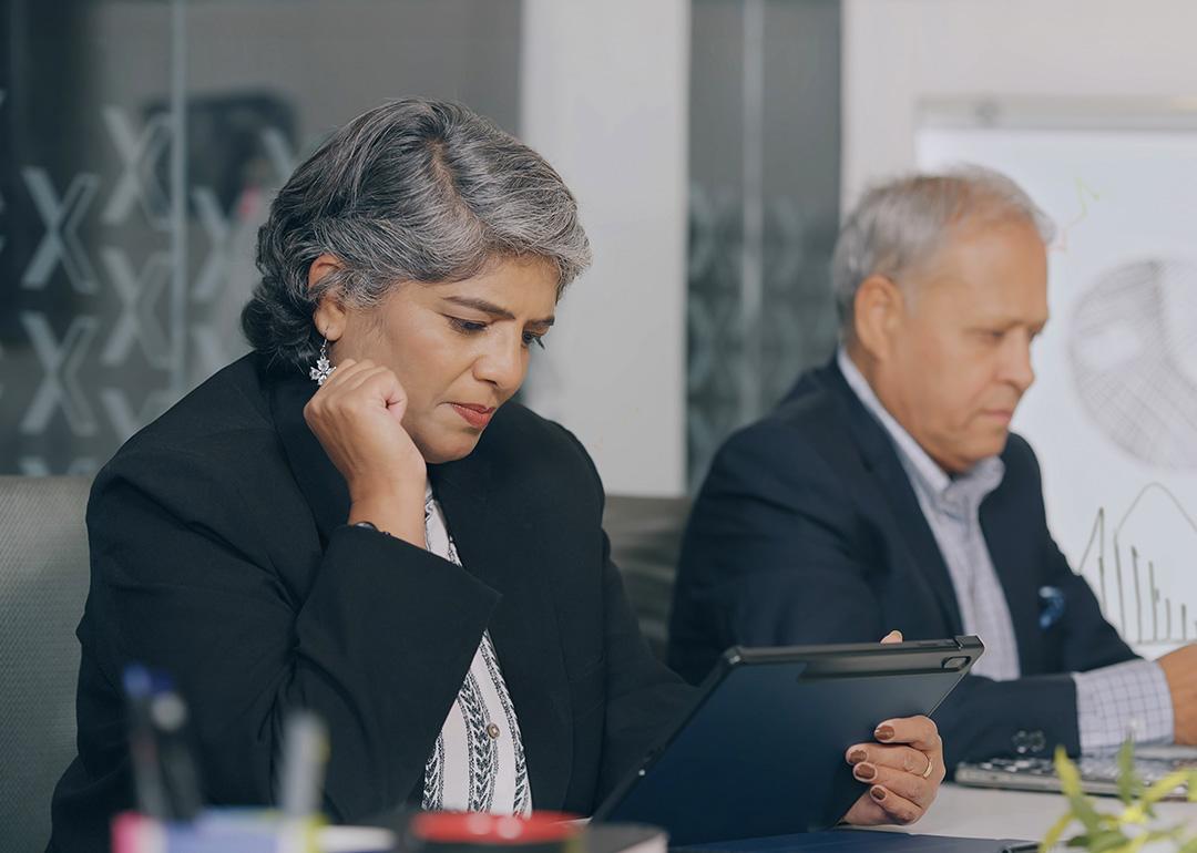 Two senior businesspeople reviewing reports at an office.