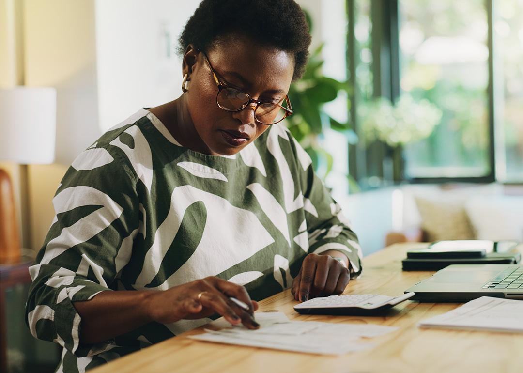 A black woman reviewing and calculating financial reports at home.