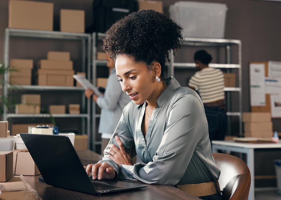 A female businesswoman working with a laptop at a logistics warehouse.