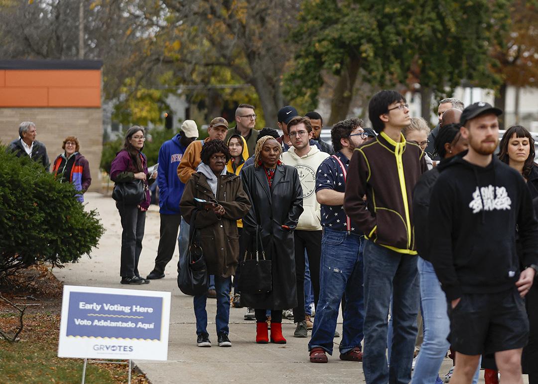 People wait in line to vote during early voting for the 2024 US general election at a polling station at Ottawa Hills High School in Grand Rapids, Michigan.