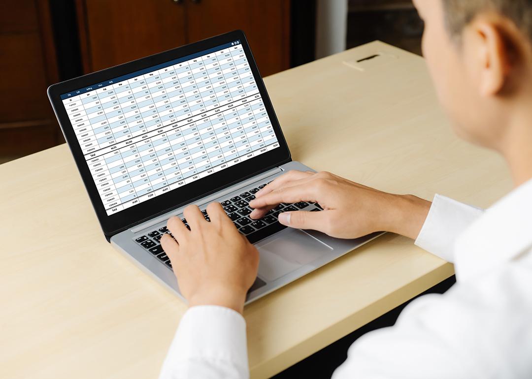 An accountant using a laptop showing financial statement spreadsheets and account balances.