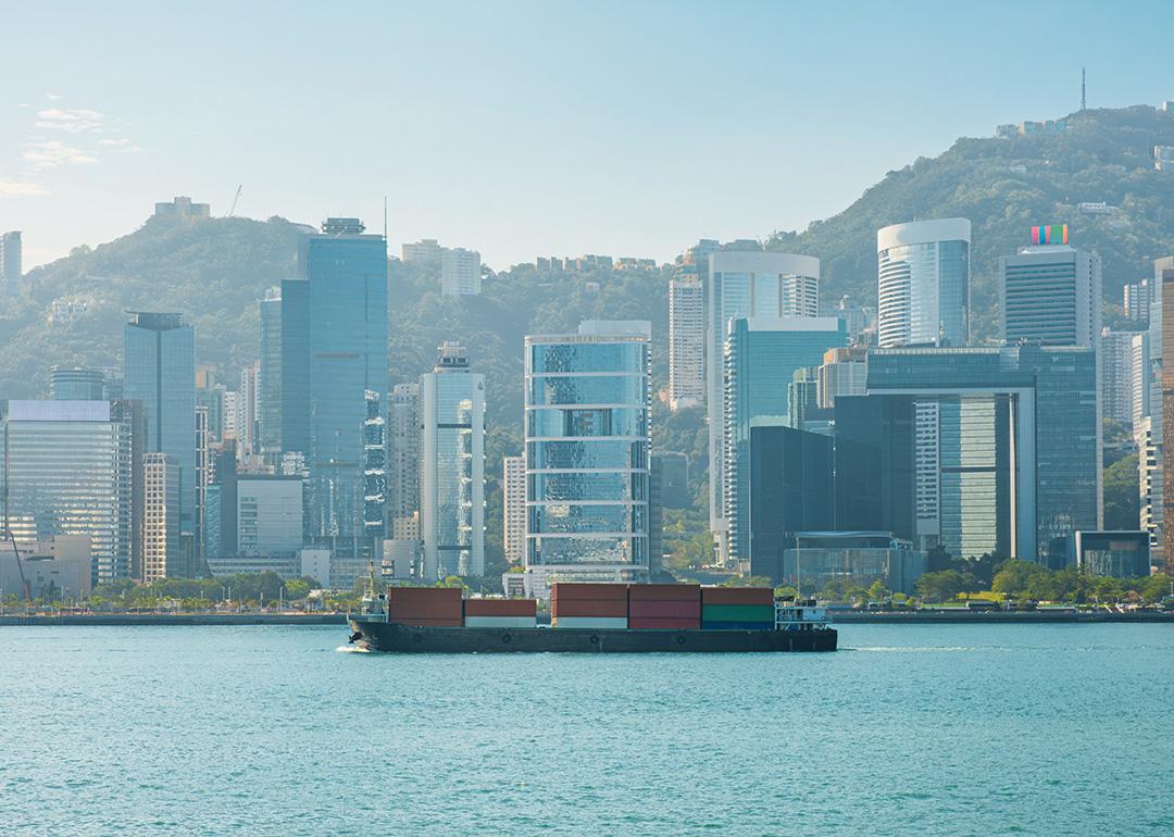 A cargo ship on the Victoria Harbour with the Hong Kong skyline in the background.