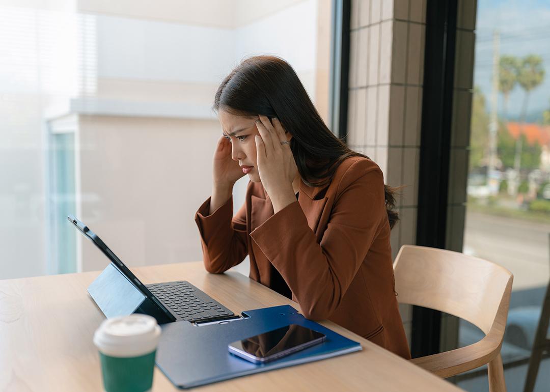 A woman employee who appears to be stressed sits in her workplace desk.