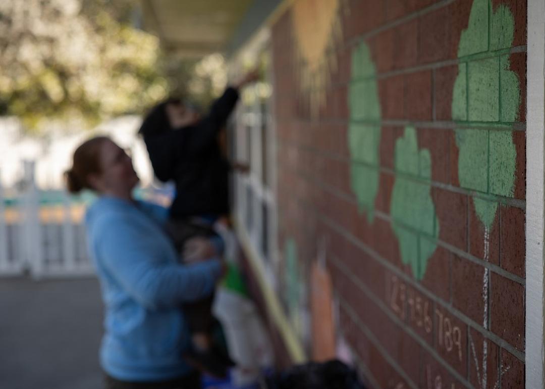 In the background, Amanda Smith, a behavioral specialist, holds up a child outside the Moore Learning Preschool & Childcare Center in Elk Grove on February 6, 2026.