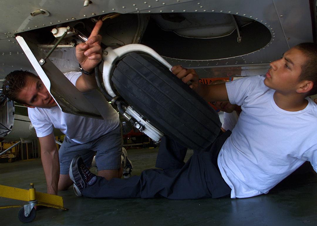 Aircraft mechanic students inspect a jet's landing gear.