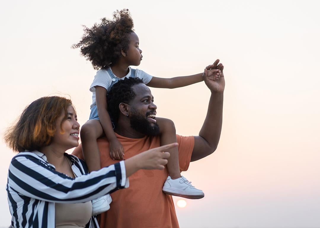 A portrait of a happy family with the daughter being carried by the father on his shoulders.