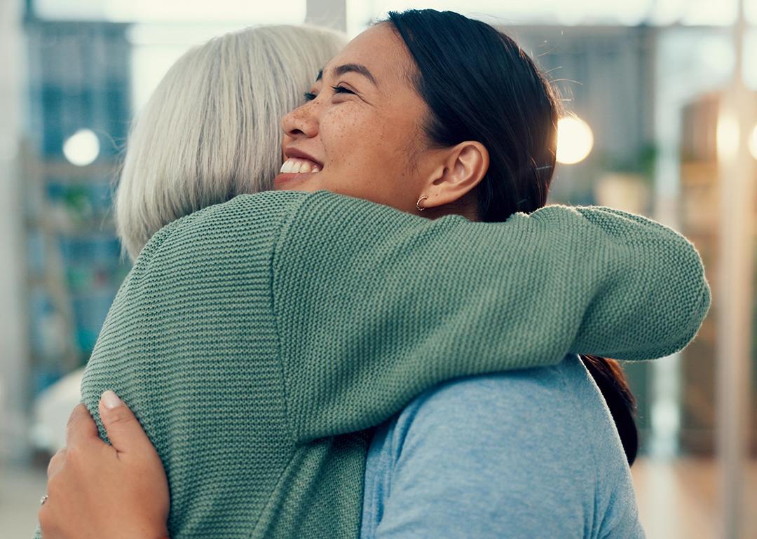 A smiling female staff member sharing a hug with an elderly woman in a physiotherapy place.
