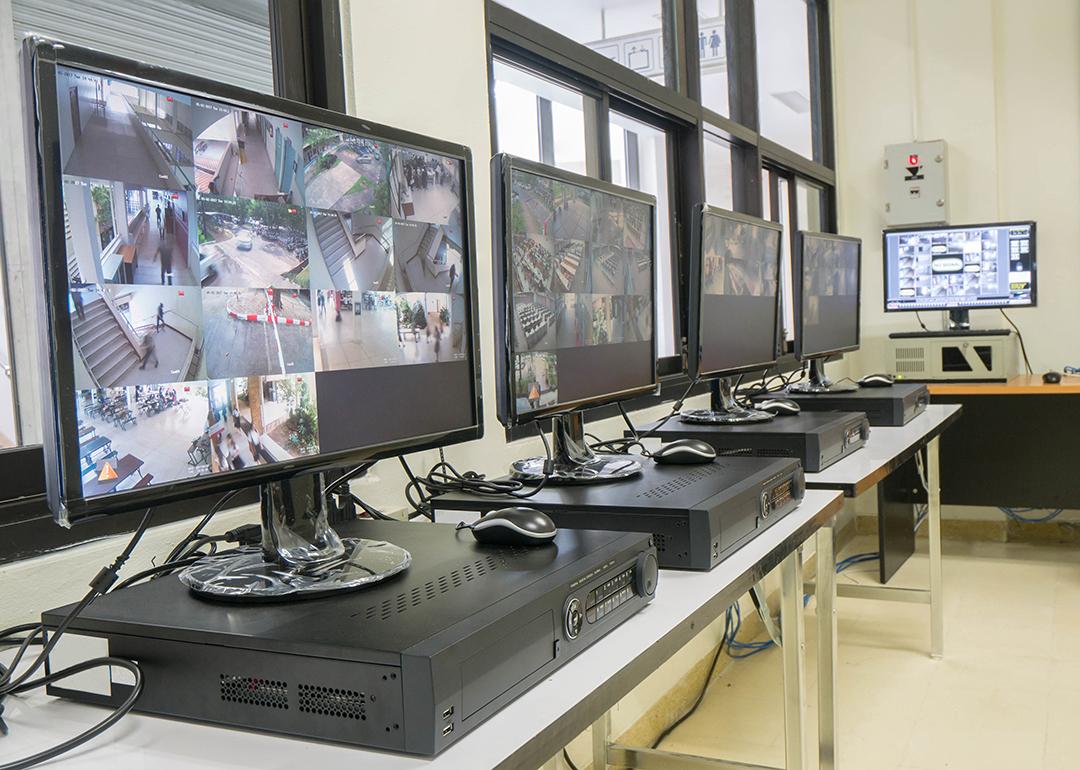 A security room with a row of monitors displaying multiple CCTV footage areas.