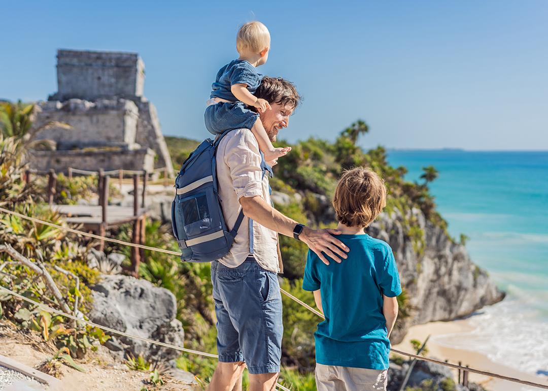 A father with his two sons enjoying the view of the pre-Columbian Mayan walled city of Tulum in Mexico.
