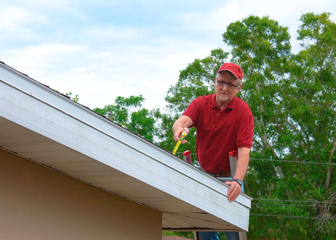 A wind mitigation inspector on a ladder doing inspection on a homeowner's new roof.