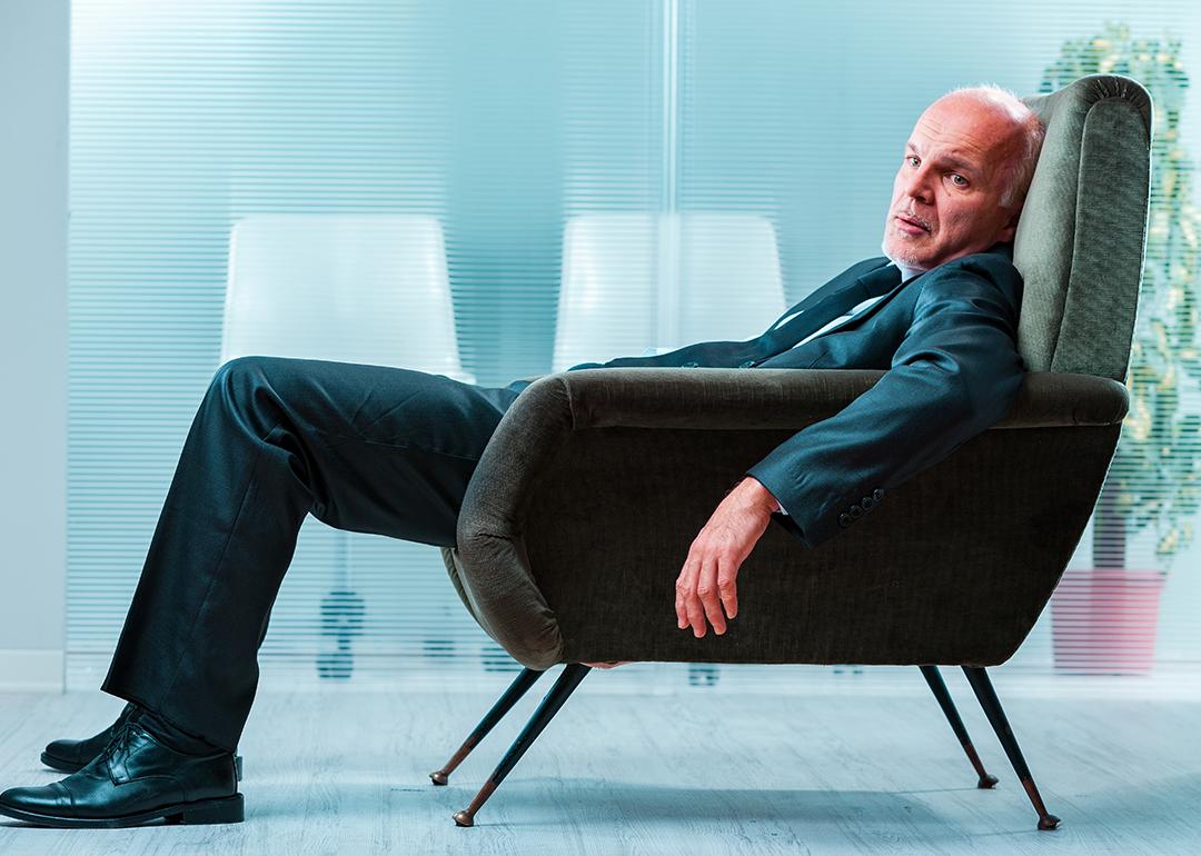 An elderly business person slouching in a chair at an office.