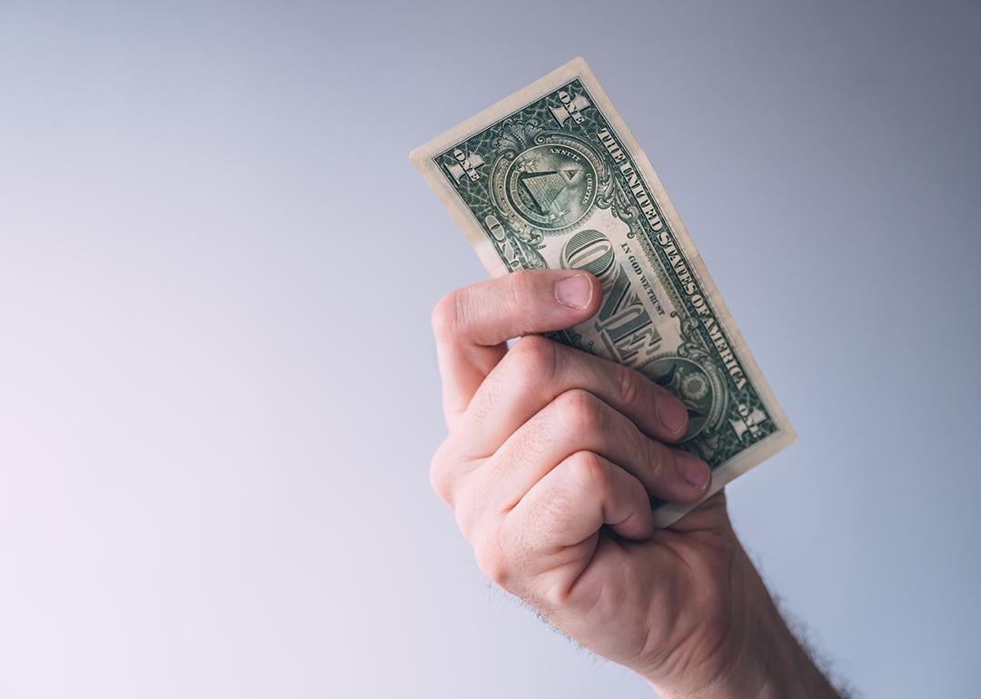 A focused photo of a person holding a one dollar bill.