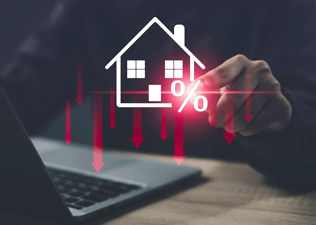 Person using a laptop illustrated with graphics showing concept of lower costs of housing.