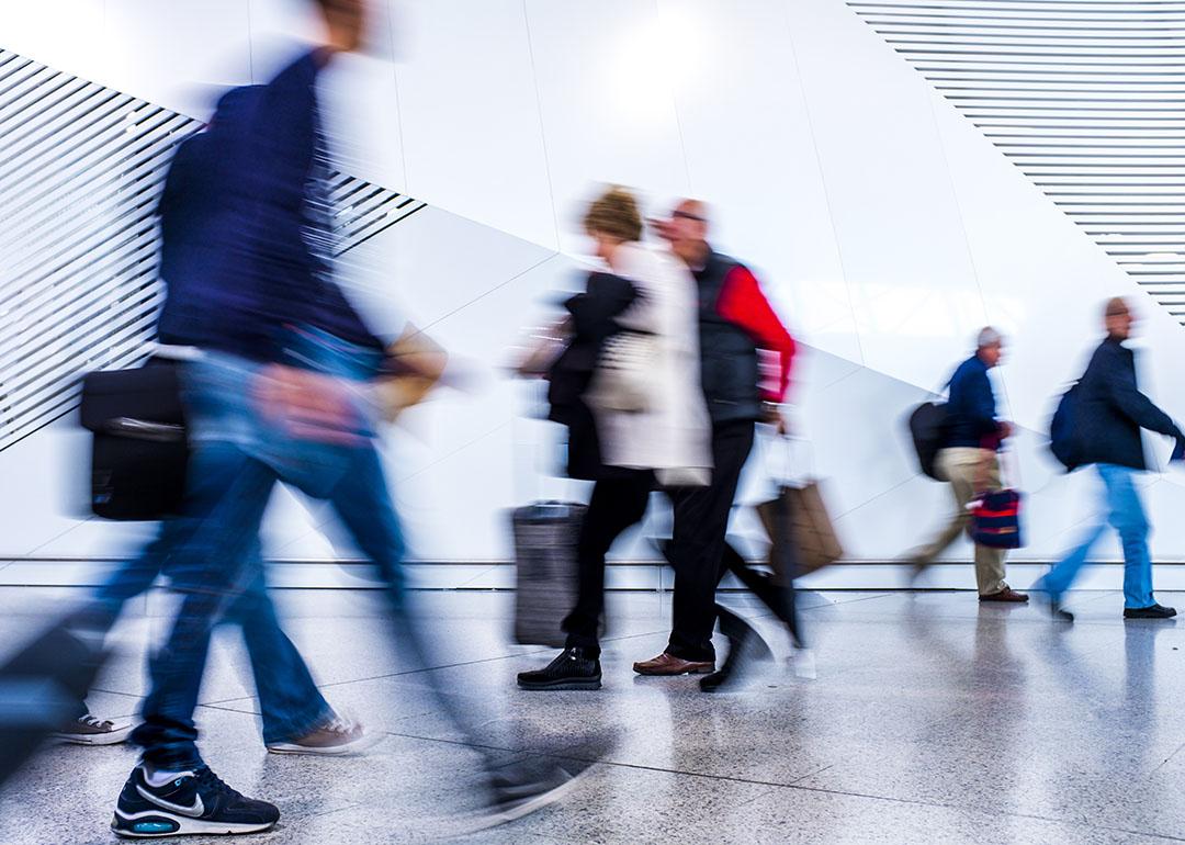 A motion blur shot of passengers walking inside an airport.