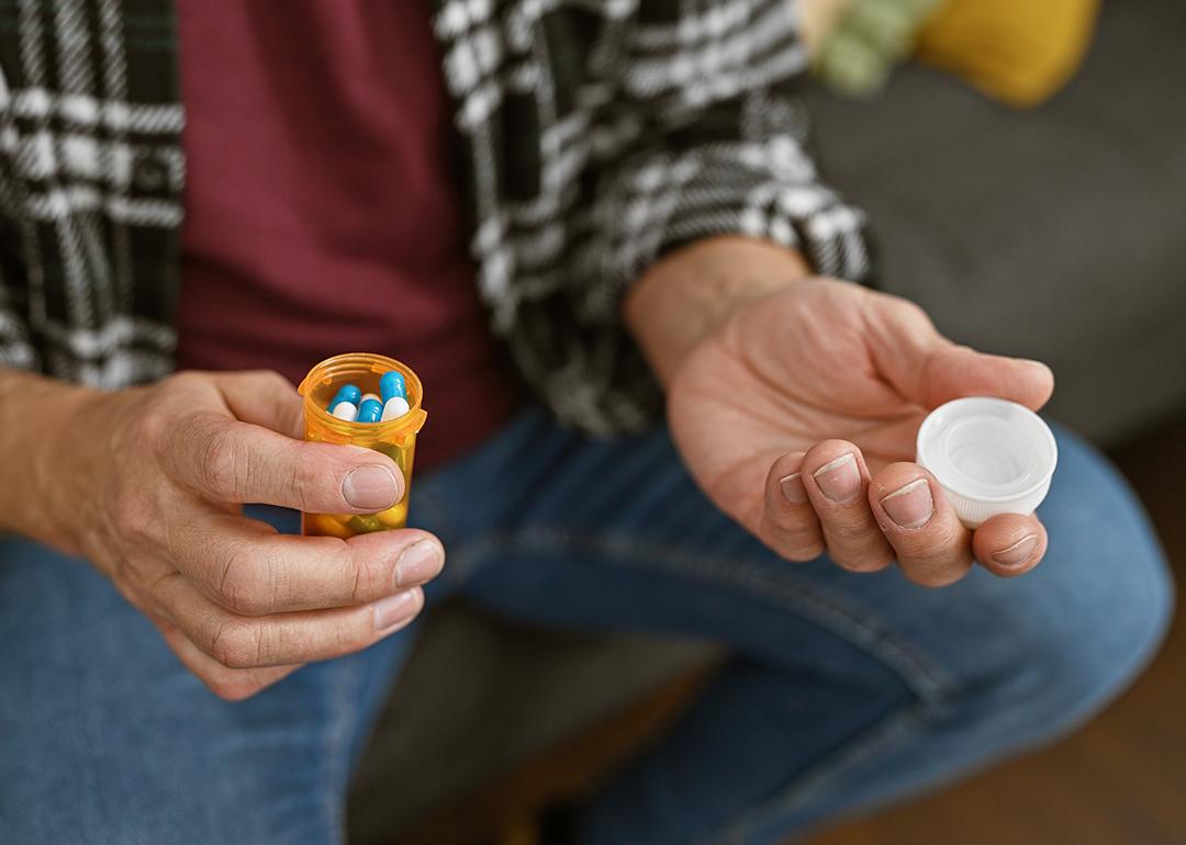 A person holding an opened medicine pill bottle. 