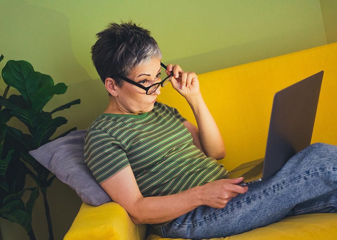 A middle aged woman skeptically browsing the internet at home.