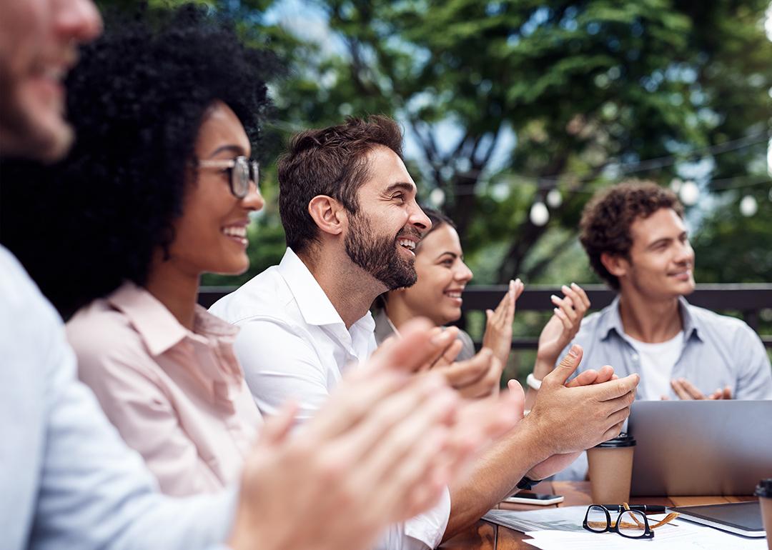 Colleagues applauding during a corporate retreat session. 
