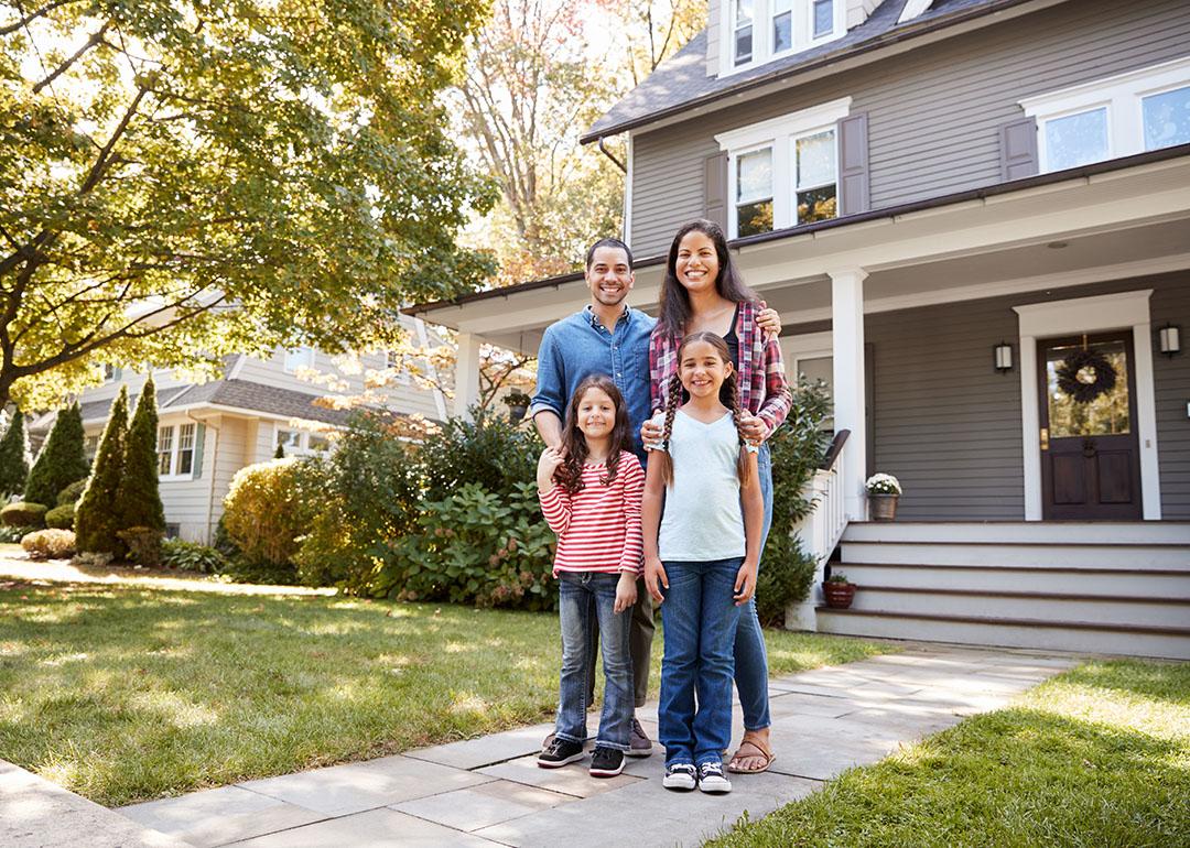 A family of four happily standing in front of their home for a photo.