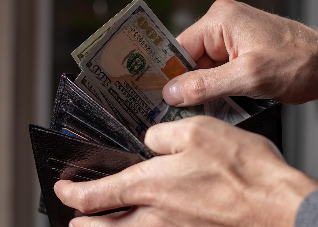 A person taking out dollar bills from a wallet.