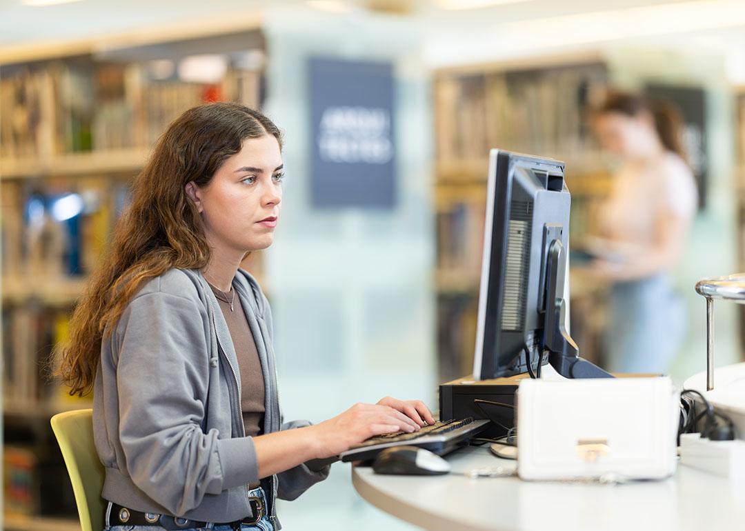 A female student using a computer at a university library.