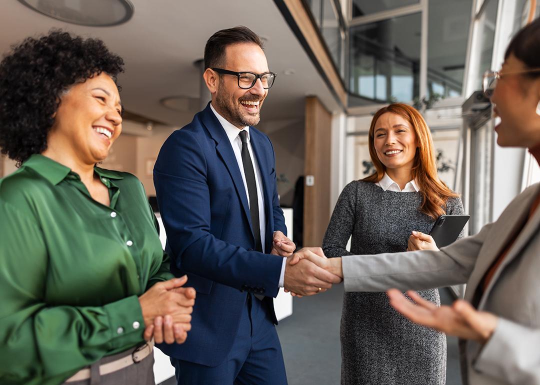 Coworkers engaging each other with handshakes in an office.