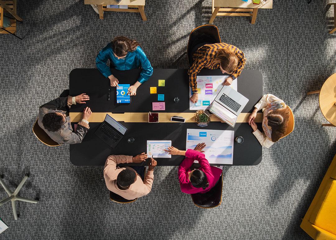 Top view of a team of entrepreneurs seated around a table in a meeting room.