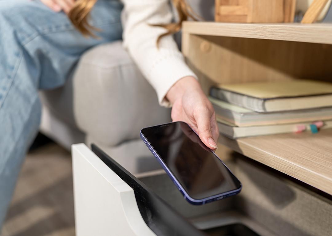 A person putting a smartphone inside a drawer.