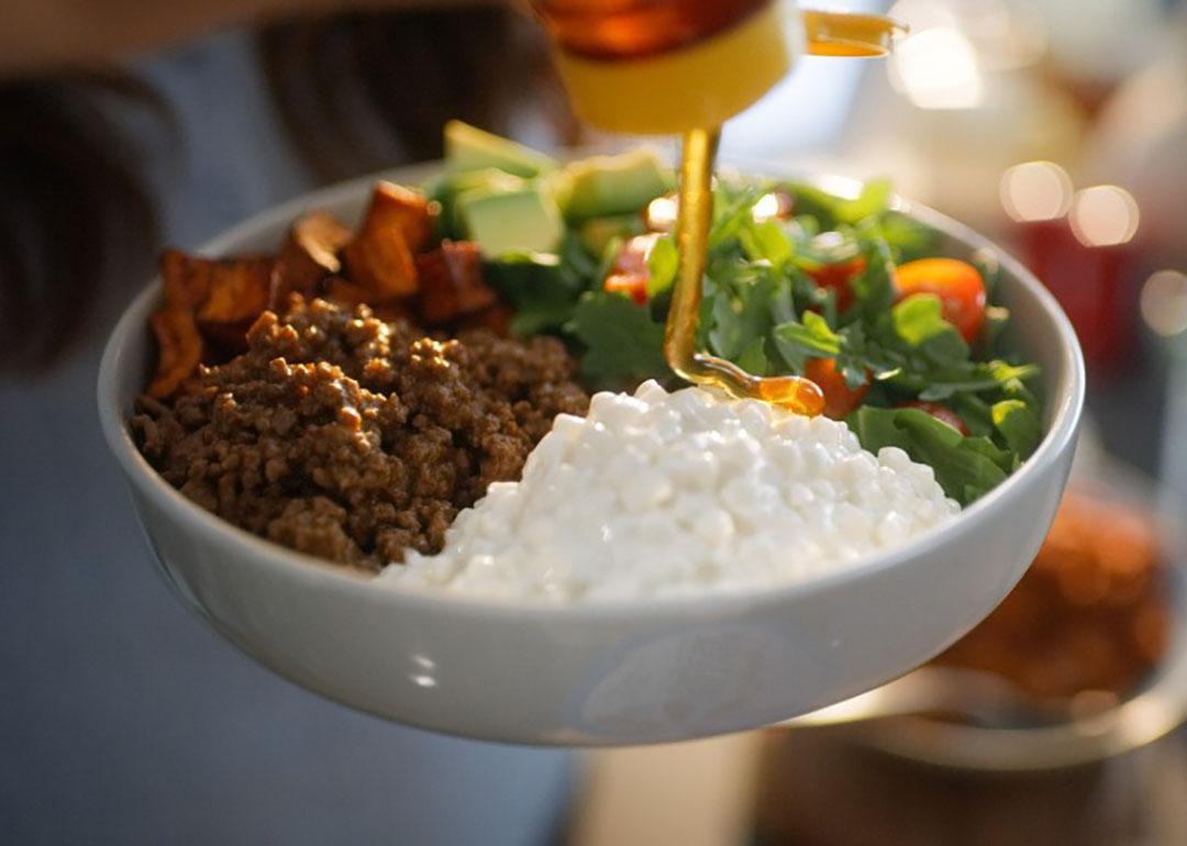 Honey poured onto a bowl of chili, cottage cheese, and salad dish for a protein-rich source meal.