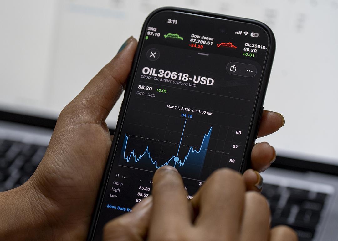 Person monitoring smartphone displaying Brent crude oil prices in USD.