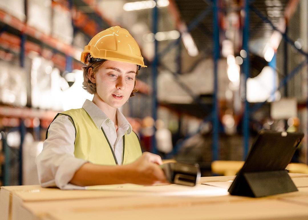 A female industrial staff in a safety suit working inside a warehouse.