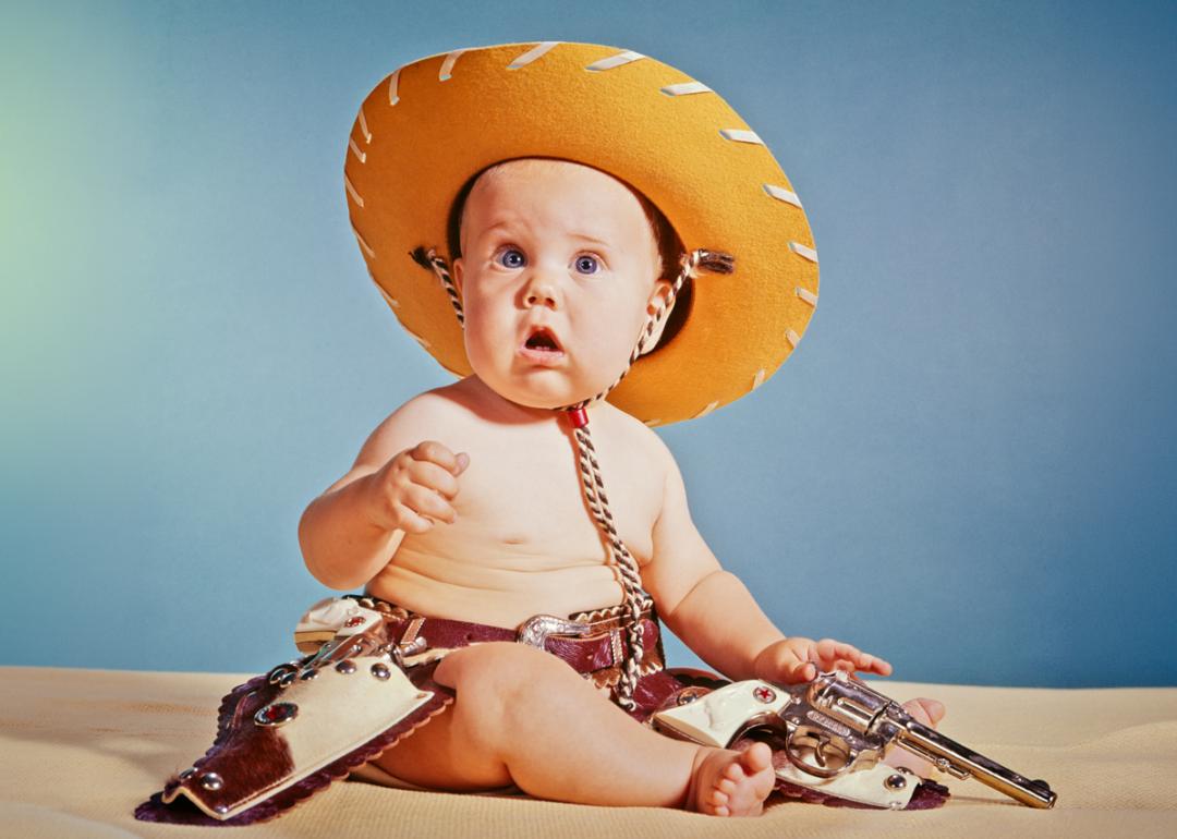 960s Baby Boy With Surprised Facial Expression Dressed As Cowboy Wearing Hat And Holster And Gun