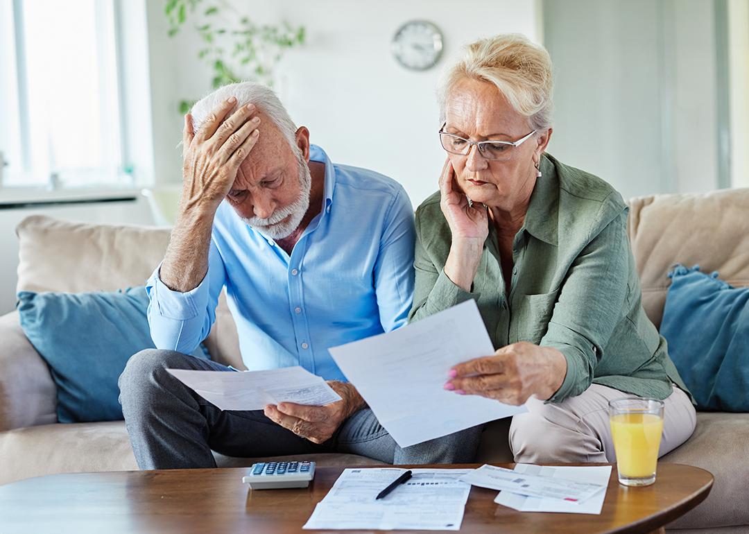An elderly couple checking bills at home. 
