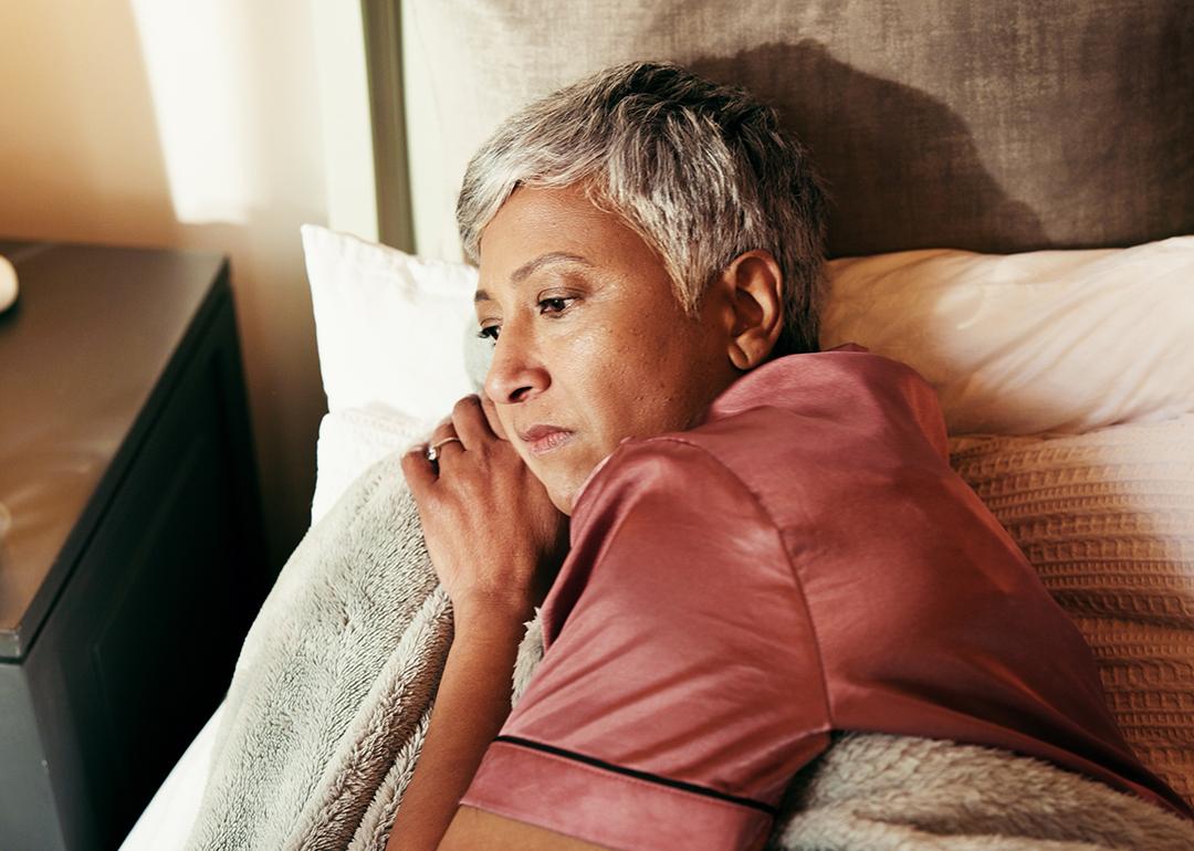 A middle-aged woman lying in bed in deep thought.