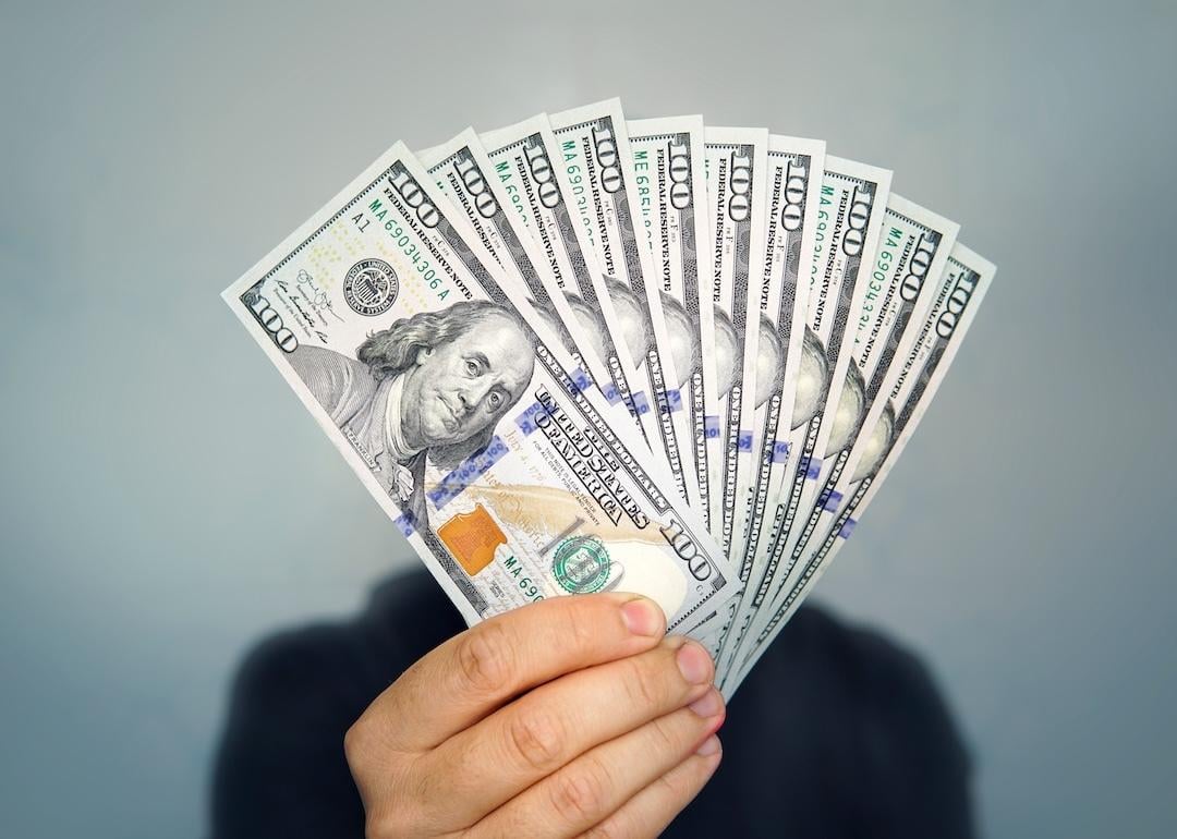A focused shot of a hand holding dollar bills. 