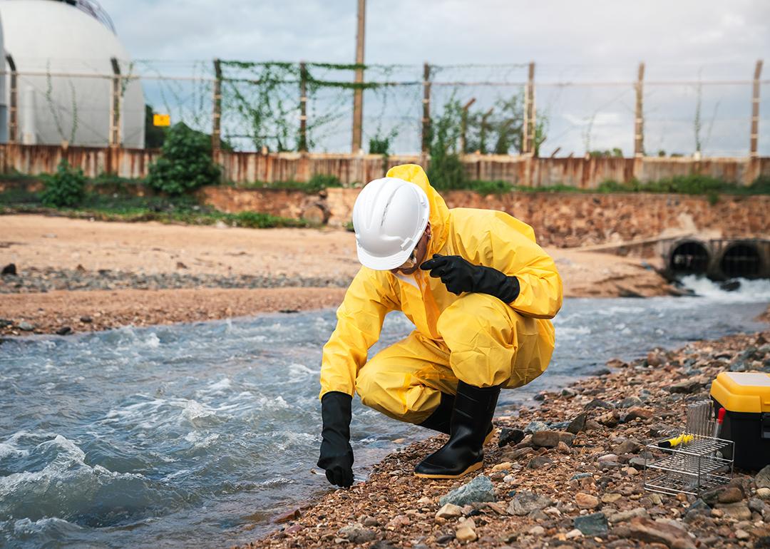 A factory worker in hazmat suit performs environmental inspection.