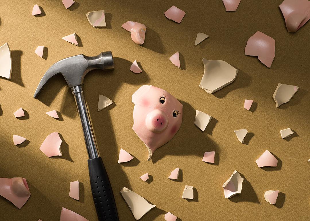 A broken piggy bank and a hammer on the floor.