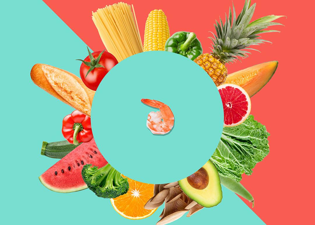 Bread, grains, fruits, and vegetables arranged in a circular pattern around a shrimp at the center. 