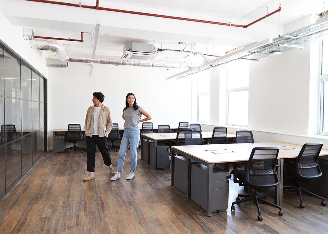 Colleagues looking around an empty modern office for startup plans.