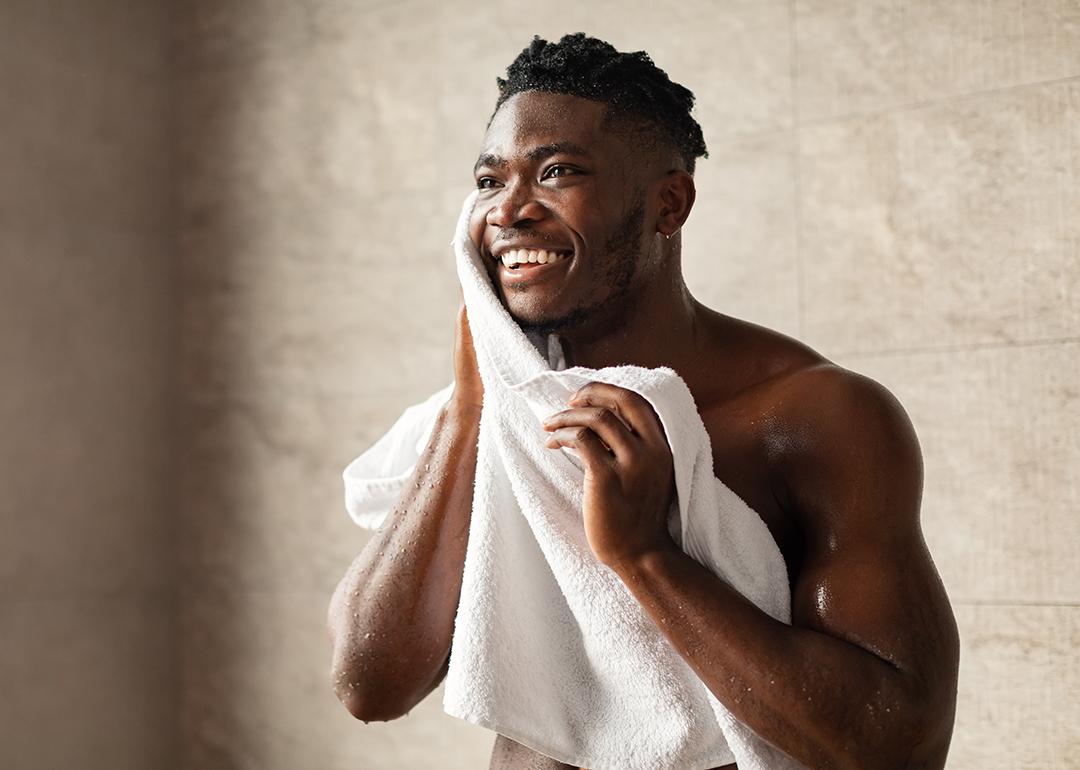 A person wiping his face with a towel after a shower.
