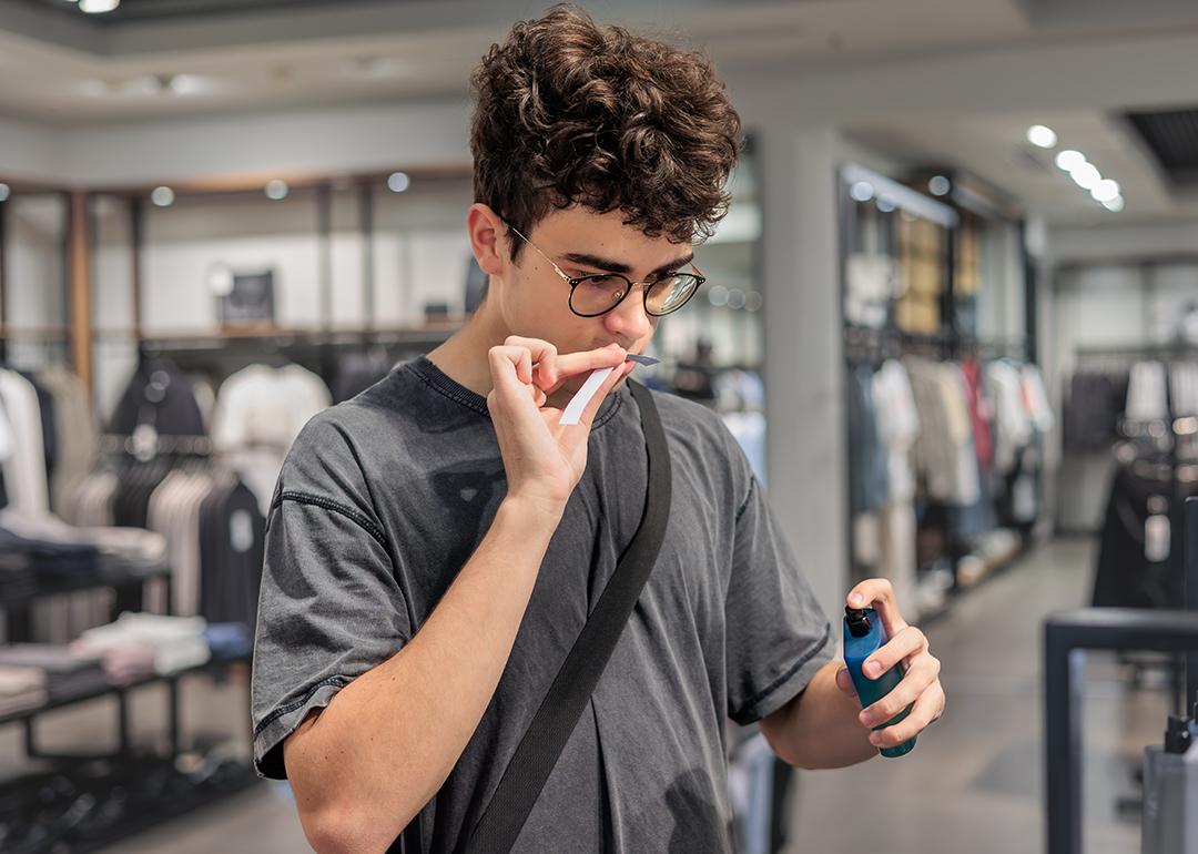 A person smelling a perfume's scent blotter in a store. 