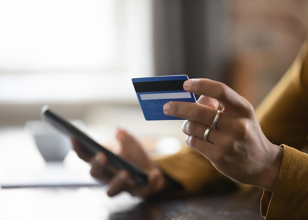 Female customer using a credit card and checking a phone.