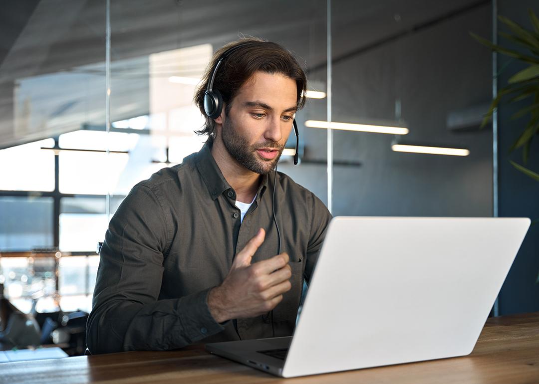 A male customer support service employee in an office working on a call with a client.