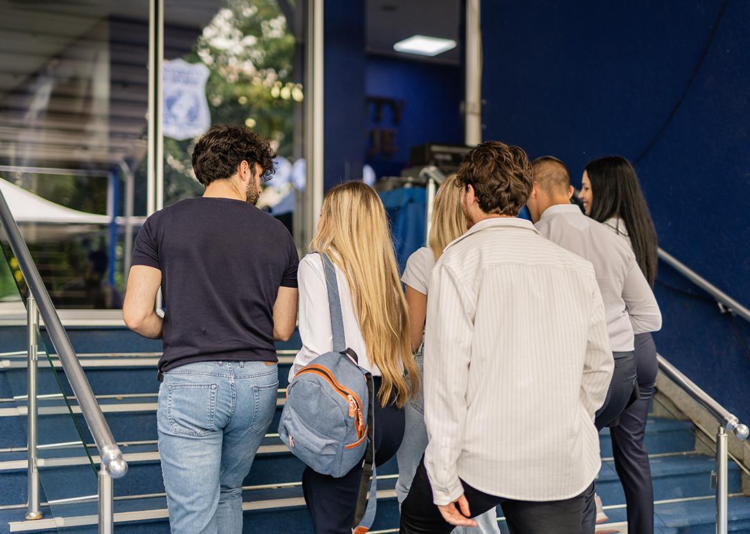 Five college students walking upstairs for a class.
