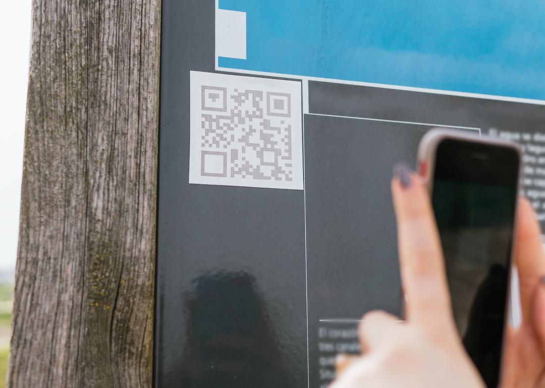 User scanning a QR code on a wall with a phone.
