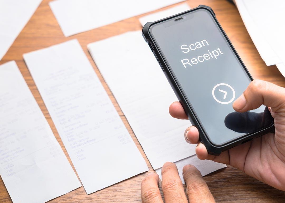 A person scanning paper receipts from a smartphone.