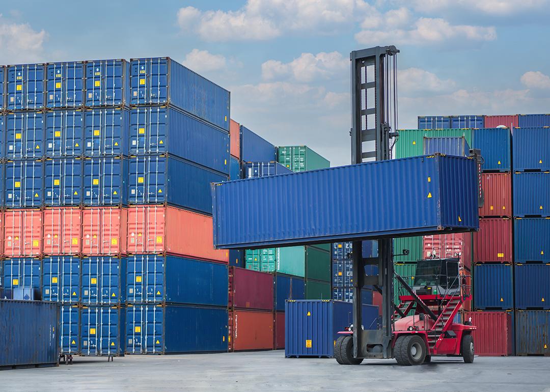 A forklift lifting a container van in a shipping yard.