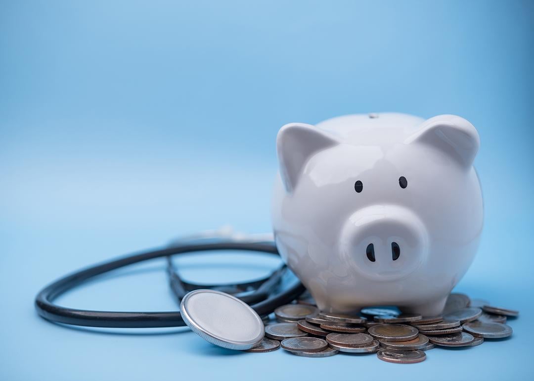 A piggy bank with coins and a stethoscope.