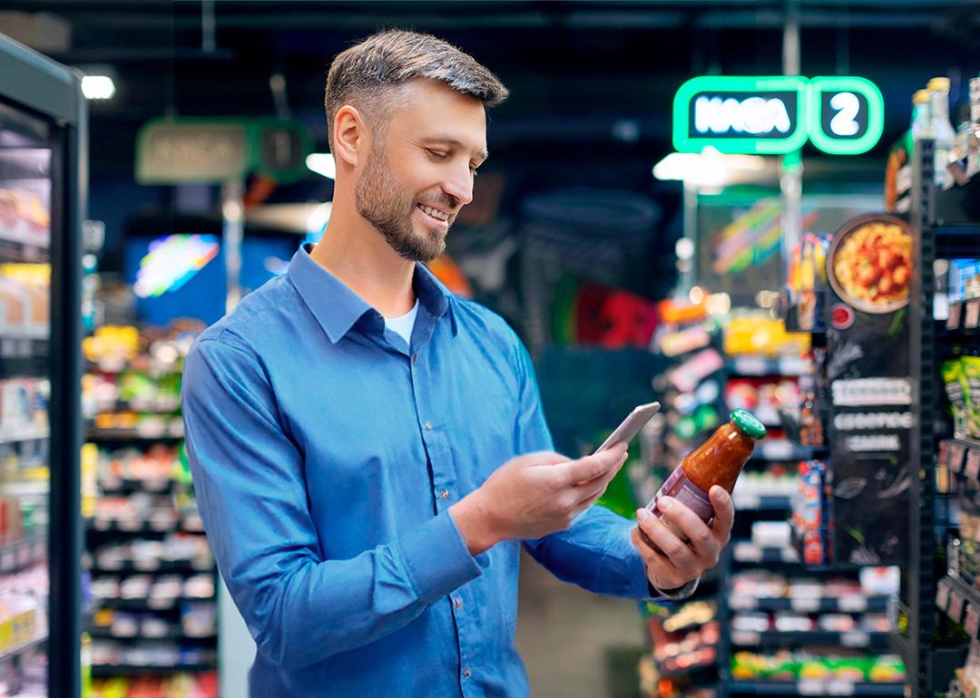Man at a supermarket scanning the QR code of a tomato sauce item.